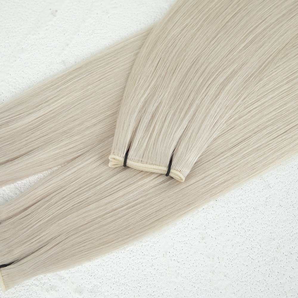 Light blonde hair extensions arranged neatly on a light textured surface, showcasing their sleek, glossy finish for hairstyling options.