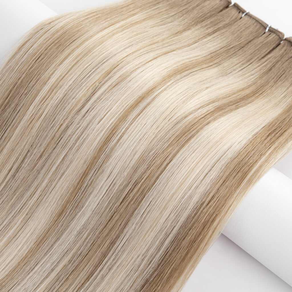 Long, straight hair extensions in a blend of blonde shades, showcasing a smooth texture and highlighting potential styling options.