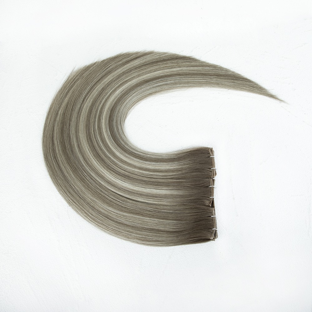 Gray hair extensions arranged in a flowing curve, showcasing their smooth texture and clip attachments against a light background.