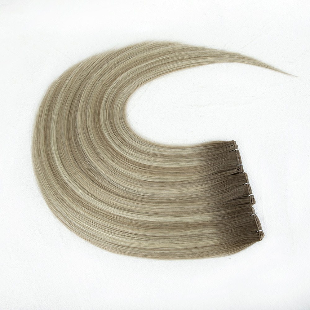 Long, straight, blonde-brown hair extensions arranged in a flowing curve, showcasing their sleek texture against a light background.