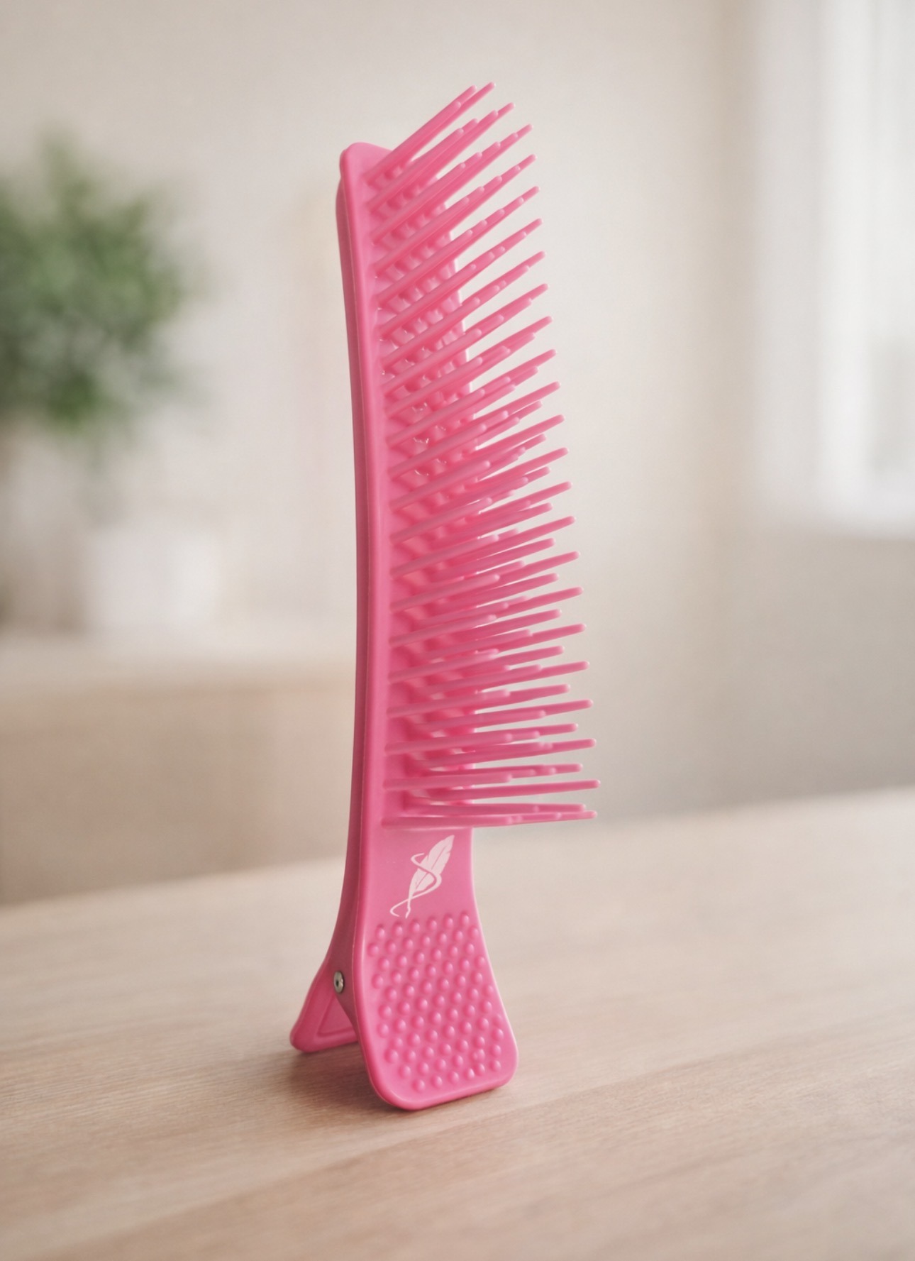 Bright pink comb displayed vertically on a wooden surface, highlighting its modern design. Ideal for hair care discussions or beauty product features.